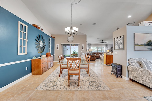 tiled dining room with lofted ceiling, a wood stove, and ceiling fan with notable chandelier