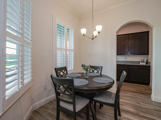 dining room with a wealth of natural light, crown molding, and a chandelier