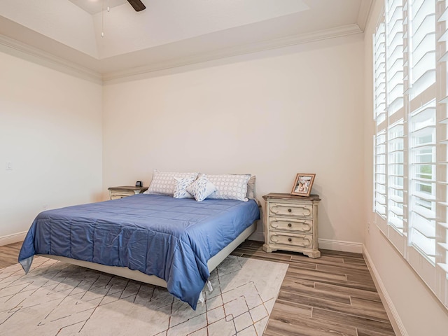 bedroom with ceiling fan, hardwood / wood-style flooring, ornamental molding, and a raised ceiling