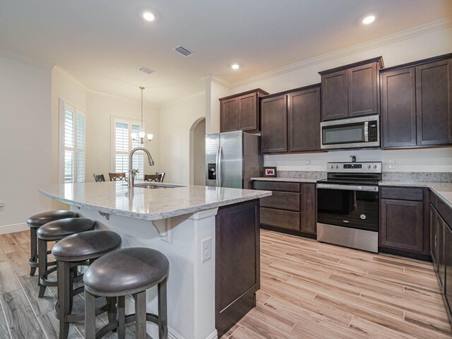 kitchen featuring a kitchen bar, appliances with stainless steel finishes, a kitchen island with sink, pendant lighting, and sink