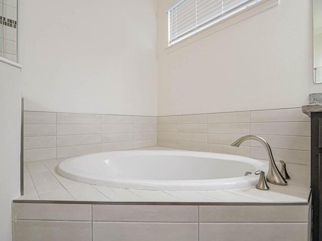 bathroom with vanity and tiled tub