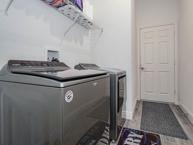 laundry area featuring wood-type flooring and washing machine and clothes dryer