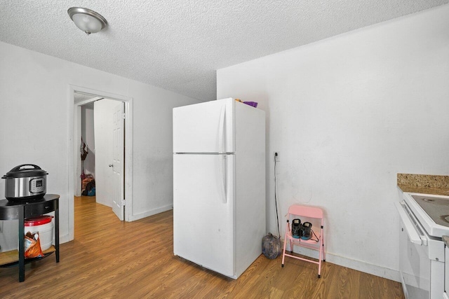 kitchen with light wood-type flooring, a textured ceiling, white cabinets, and white appliances