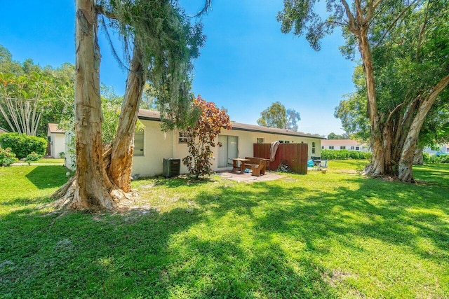 rear view of house featuring a lawn and central AC unit