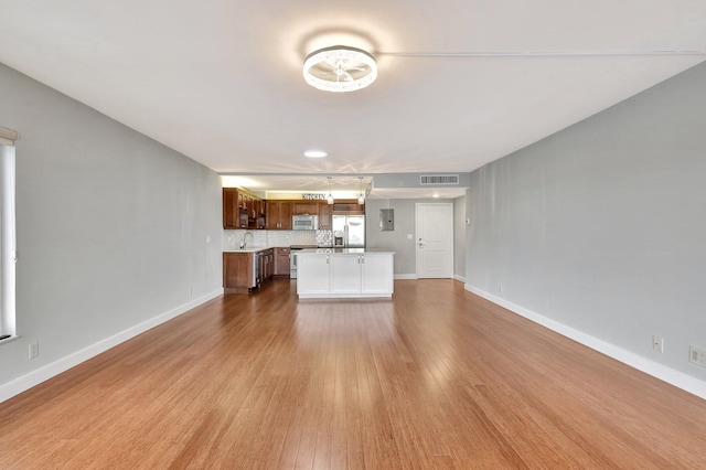 unfurnished living room with sink and light hardwood / wood-style flooring