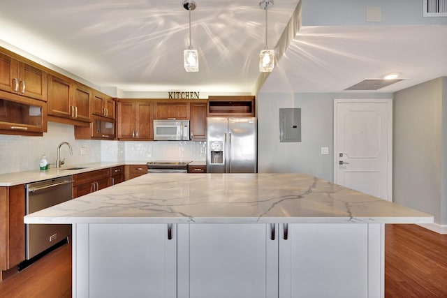 kitchen with appliances with stainless steel finishes, hanging light fixtures, a center island, electric panel, and light stone countertops