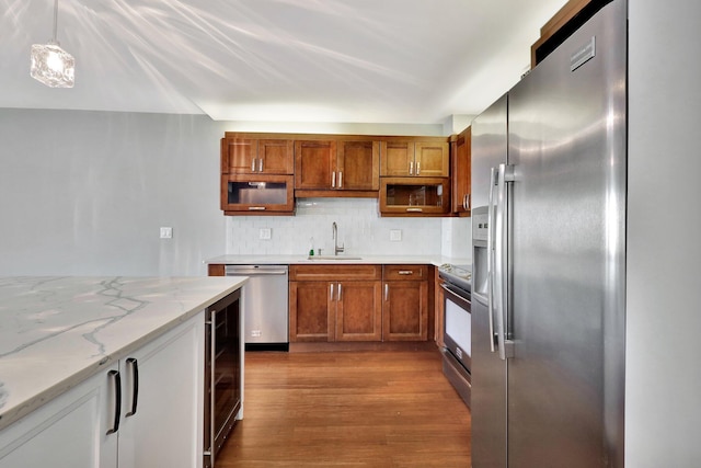 kitchen with sink, hanging light fixtures, stainless steel appliances, tasteful backsplash, and light stone countertops