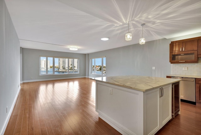 kitchen featuring hanging light fixtures, light stone countertops, a kitchen island, decorative backsplash, and stainless steel dishwasher