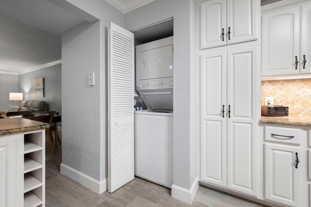 laundry room featuring ornamental molding, stacked washer and dryer, and light wood-type flooring