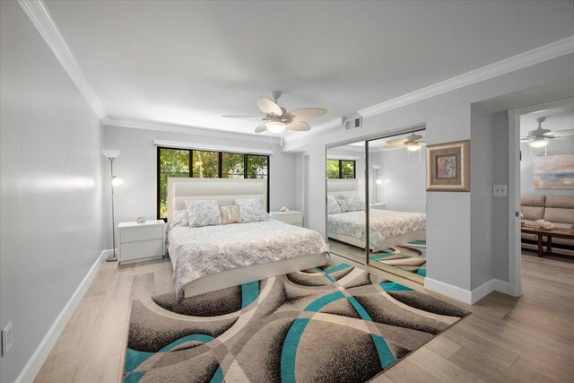 bedroom featuring a closet, ceiling fan, light wood-type flooring, and crown molding