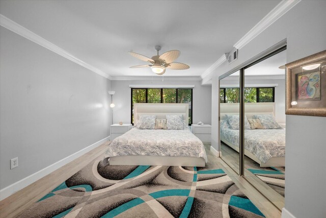 bedroom with wood-type flooring, ornamental molding, ceiling fan, and multiple windows