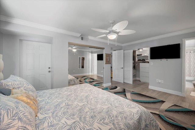 bedroom with ensuite bathroom, ceiling fan, hardwood / wood-style flooring, two closets, and ornamental molding