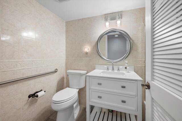 bathroom with tile walls, toilet, and vanity with extensive cabinet space