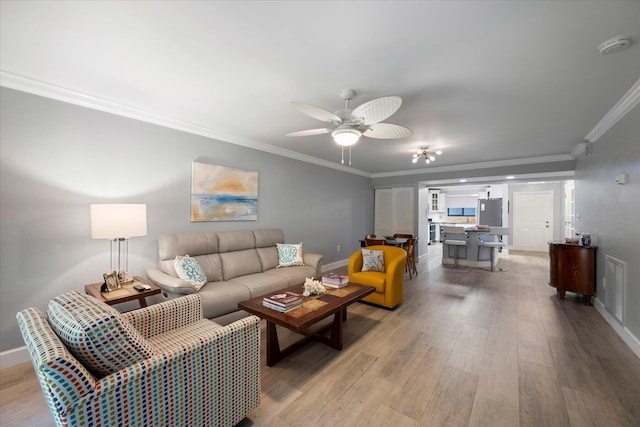 living room featuring crown molding, visible vents, ceiling fan, light wood-type flooring, and baseboards