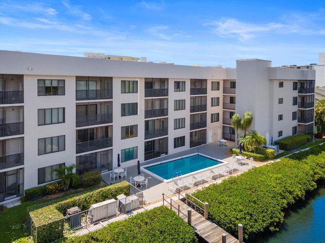 community pool featuring a water view, a patio area, and fence