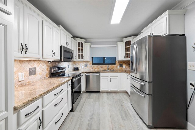 kitchen featuring light hardwood / wood-style flooring, stainless steel appliances, light stone counters, backsplash, and white cabinets