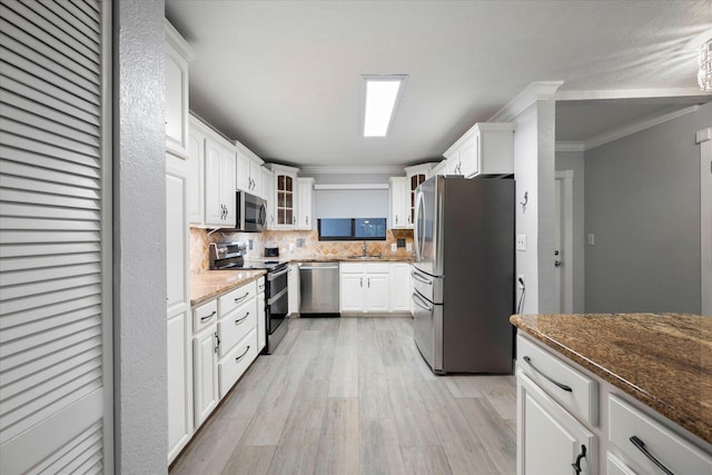 kitchen with crown molding, light hardwood / wood-style flooring, stainless steel appliances, white cabinets, and tasteful backsplash