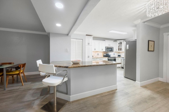 kitchen with stainless steel appliances, light hardwood / wood-style floors, white cabinets, and stone countertops