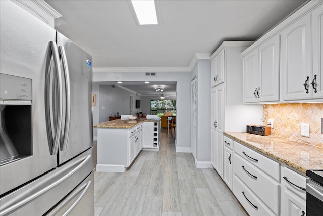 kitchen featuring white cabinets, ornamental molding, appliances with stainless steel finishes, backsplash, and light stone countertops