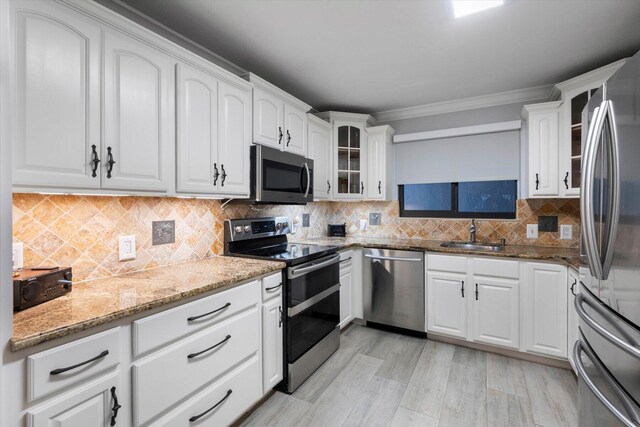 kitchen with light wood-type flooring, backsplash, white cabinetry, and appliances with stainless steel finishes