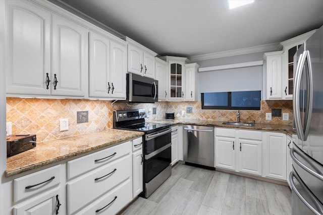 kitchen featuring stainless steel appliances, a sink, glass insert cabinets, and white cabinets