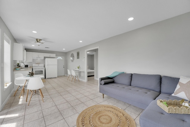 living room with ceiling fan, sink, light tile patterned floors, and a healthy amount of sunlight