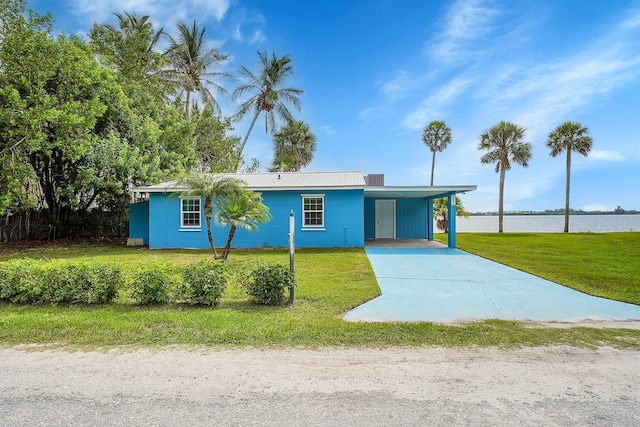 single story home with a front yard, a water view, and a carport