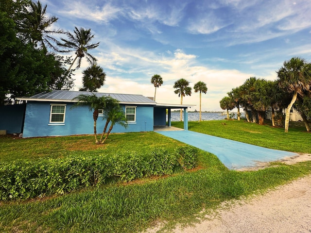 view of front of property with a front yard, a water view, and a carport