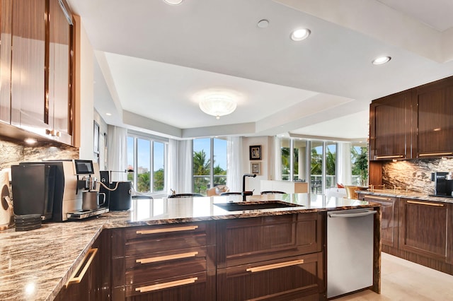 kitchen featuring dishwasher, light stone counters, sink, and tasteful backsplash