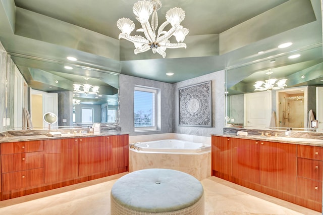 bathroom with tiled bath, vanity, and a chandelier