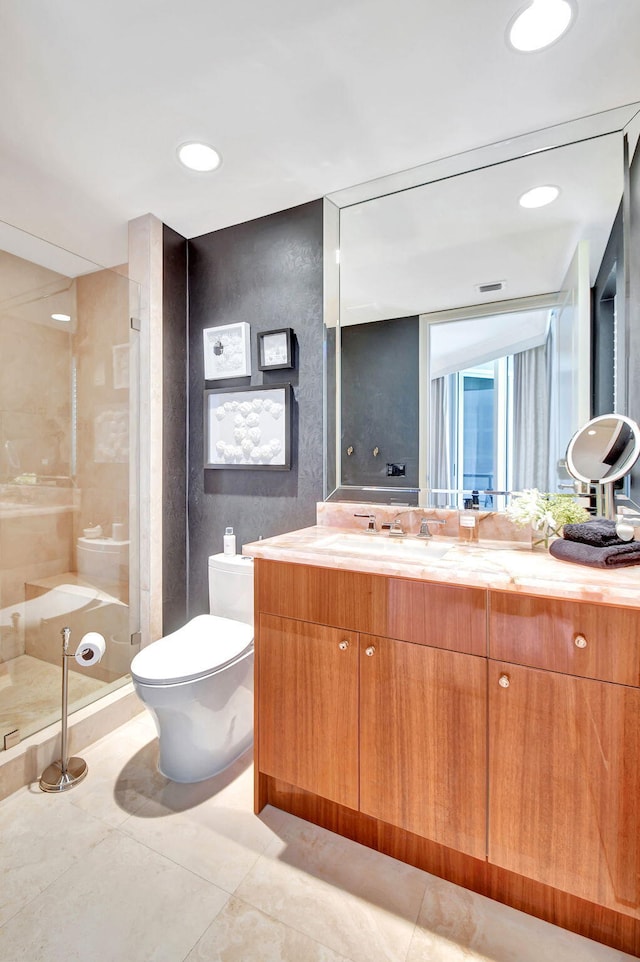 bathroom featuring tile patterned flooring, a tile shower, vanity, and toilet