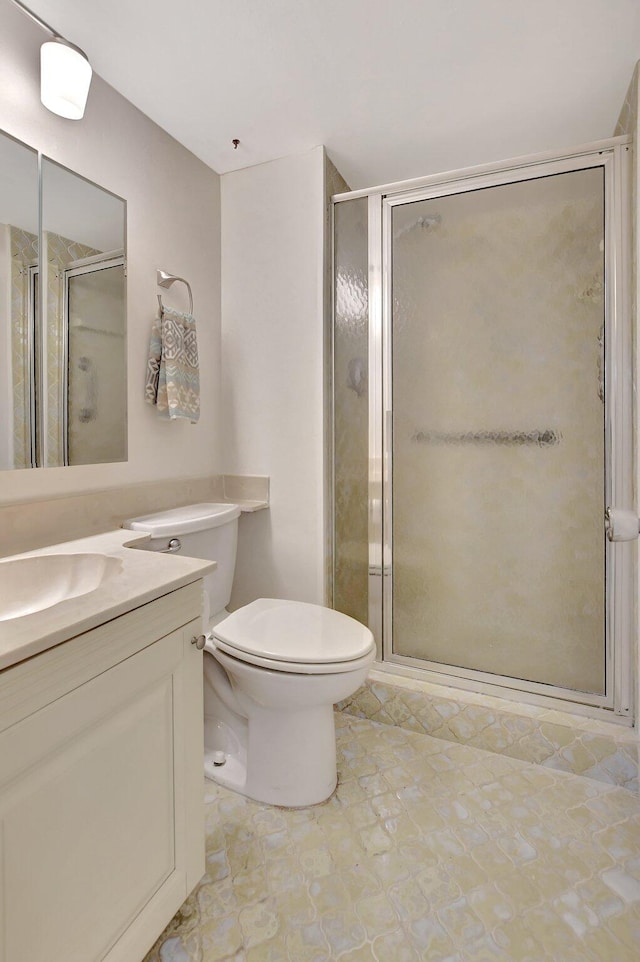 bathroom with vanity, a shower with shower door, and toilet