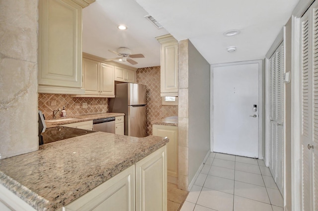 kitchen featuring light tile patterned floors, decorative backsplash, stainless steel appliances, and cream cabinetry