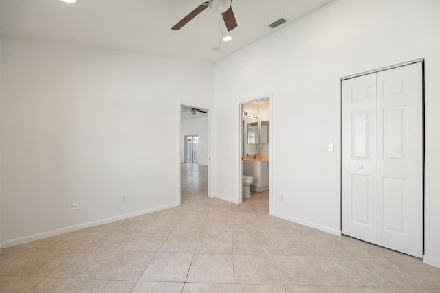 unfurnished bedroom with a closet, ensuite bath, ceiling fan, and light tile patterned flooring