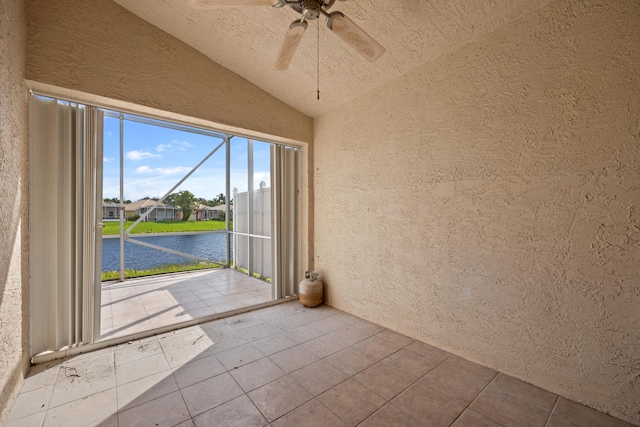 interior space featuring a water view, tile patterned floors, ceiling fan, and lofted ceiling