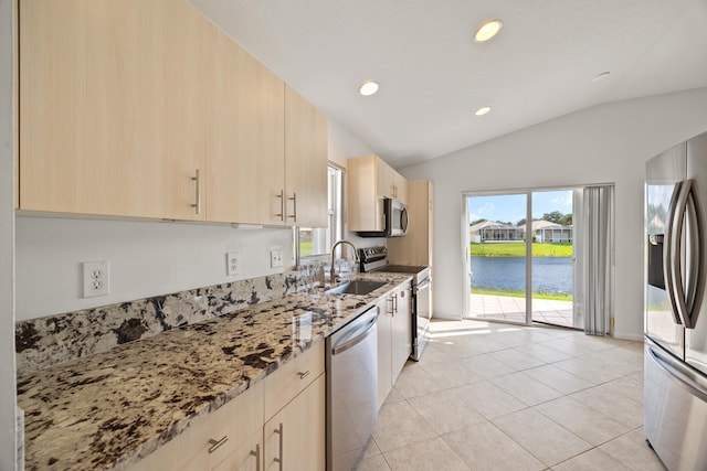 kitchen with stone counters, a water view, sink, vaulted ceiling, and stainless steel appliances