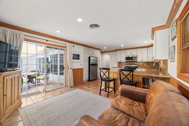 living room with crown molding, sink, and light tile flooring