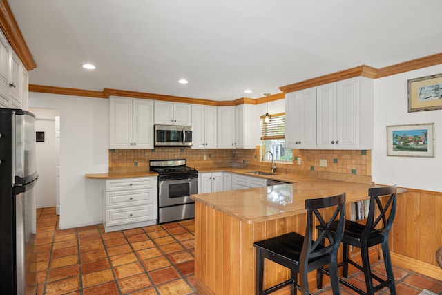 kitchen with stainless steel appliances, kitchen peninsula, backsplash, and pendant lighting