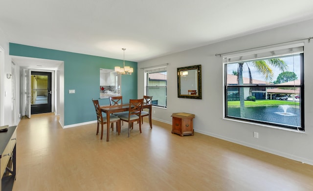 dining space with light hardwood / wood-style flooring and an inviting chandelier