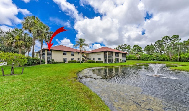 rear view of house with a water view and a lawn