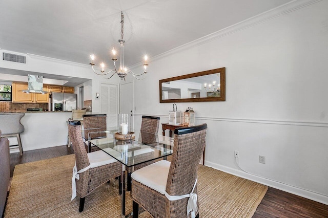 dining space featuring dark hardwood / wood-style flooring, ornamental molding, and an inviting chandelier