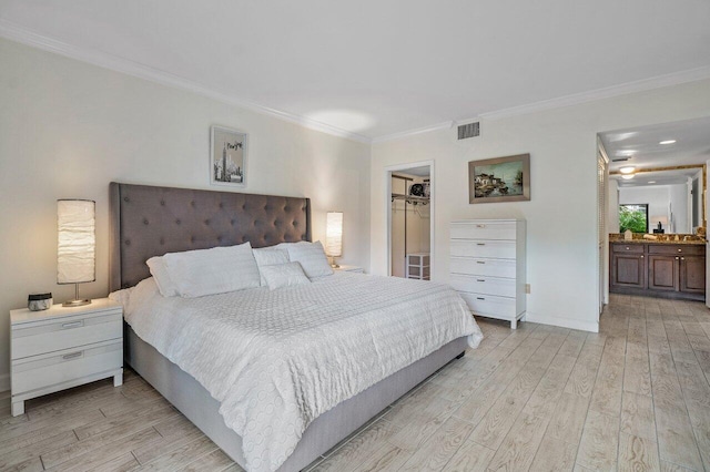 bedroom featuring ensuite bathroom, a spacious closet, light wood-type flooring, ornamental molding, and a closet