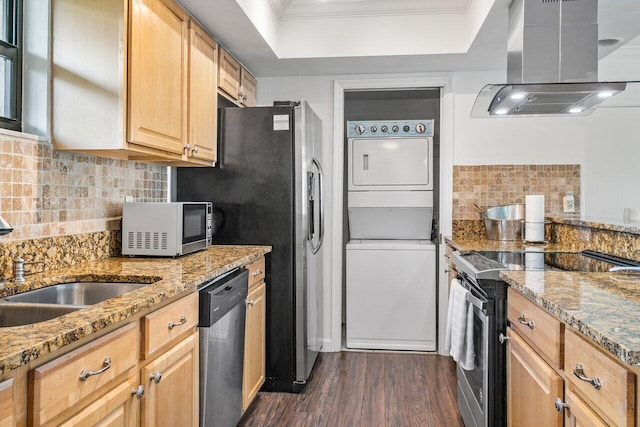 kitchen with island exhaust hood, light stone countertops, dark hardwood / wood-style flooring, stainless steel appliances, and stacked washer / drying machine