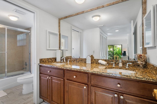 full bathroom with hardwood / wood-style floors, vanity, toilet, and enclosed tub / shower combo