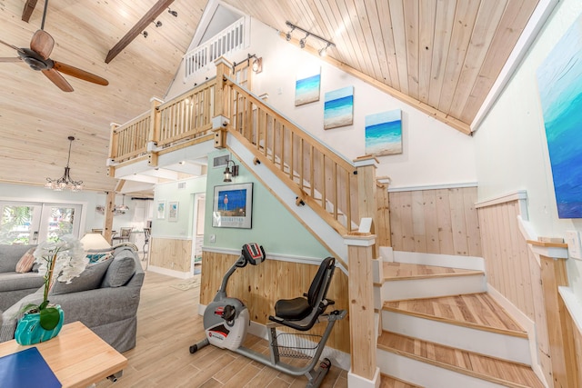 staircase with wood ceiling, hardwood / wood-style floors, wooden walls, and high vaulted ceiling