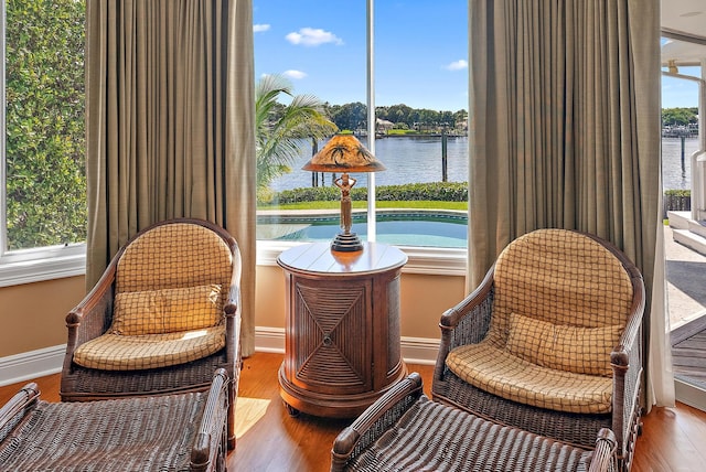 living area with hardwood / wood-style floors and a water view