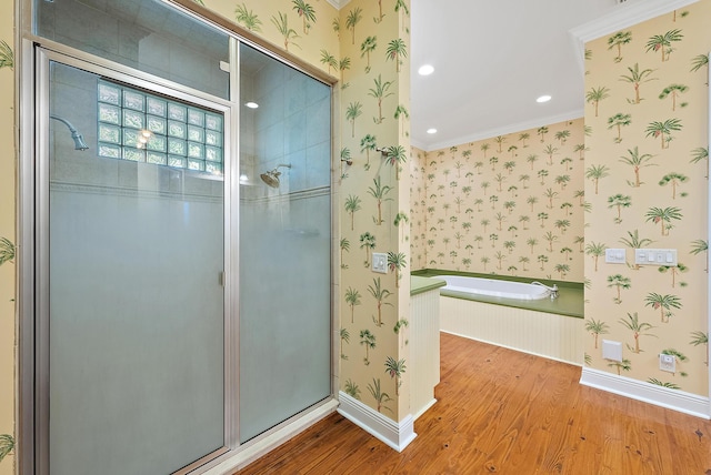 bathroom with tiled bath, hardwood / wood-style floors, and ornamental molding