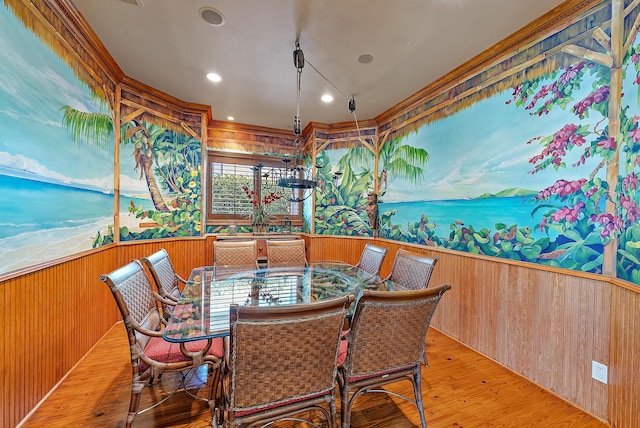 dining space with light wood-type flooring and wooden walls