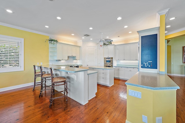 kitchen with backsplash, a center island, kitchen peninsula, and a breakfast bar area