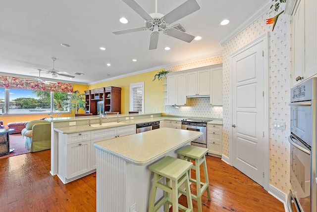 kitchen with sink, kitchen peninsula, light wood-type flooring, a breakfast bar, and crown molding